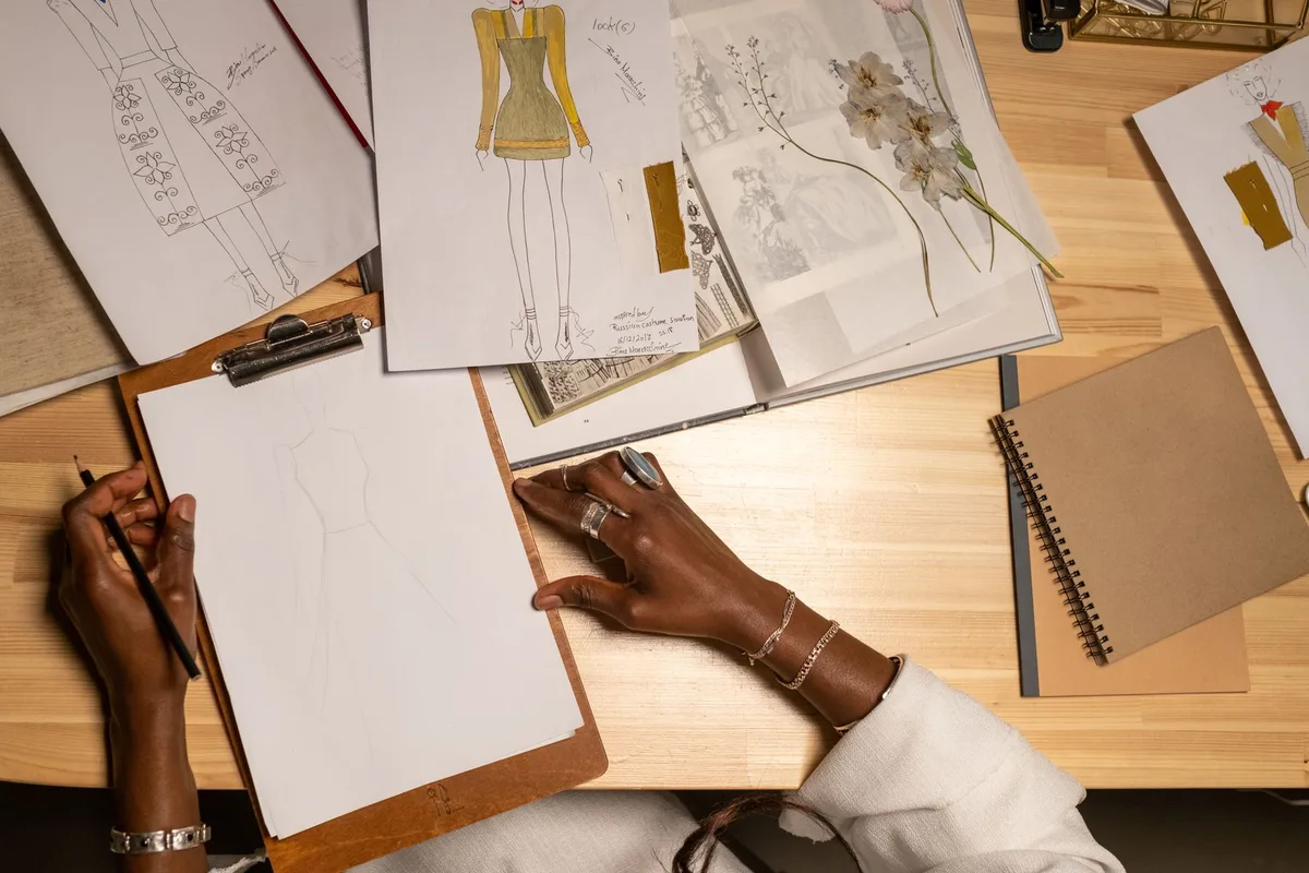Fashion sketches and design references on an atelier worktable
